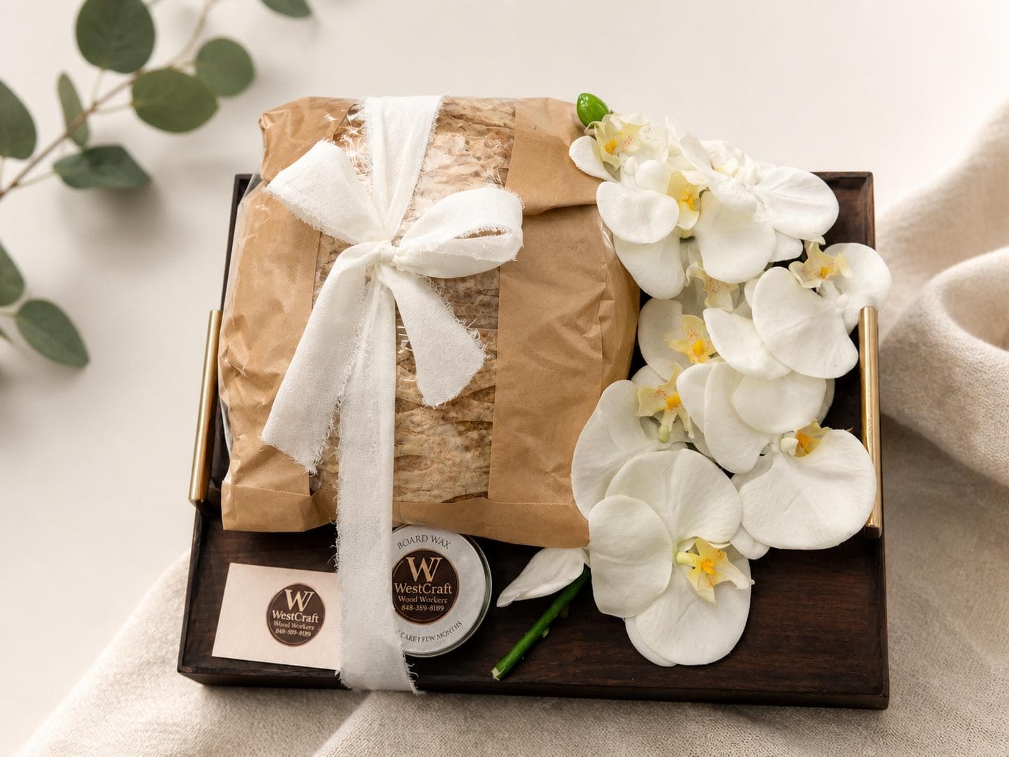 Close-up of a wrapped challah board gift with white orchids